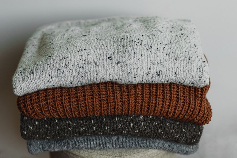 Close-up of folded cozy knit sweaters in neutral tones, perfect for autumn and winter fashion.